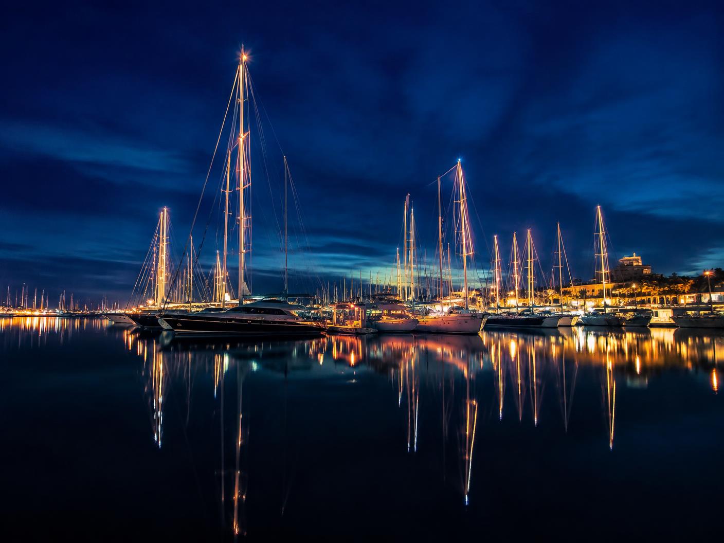 Yacht masts and lights reflected in the Sotogrande marina at night